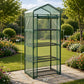 A green metal and mesh portable garden stand with three wire shelves, shown outdoors on a stone walkway in a landscaped garden. White dimension lines and text indicate height, width, and depth measurements.